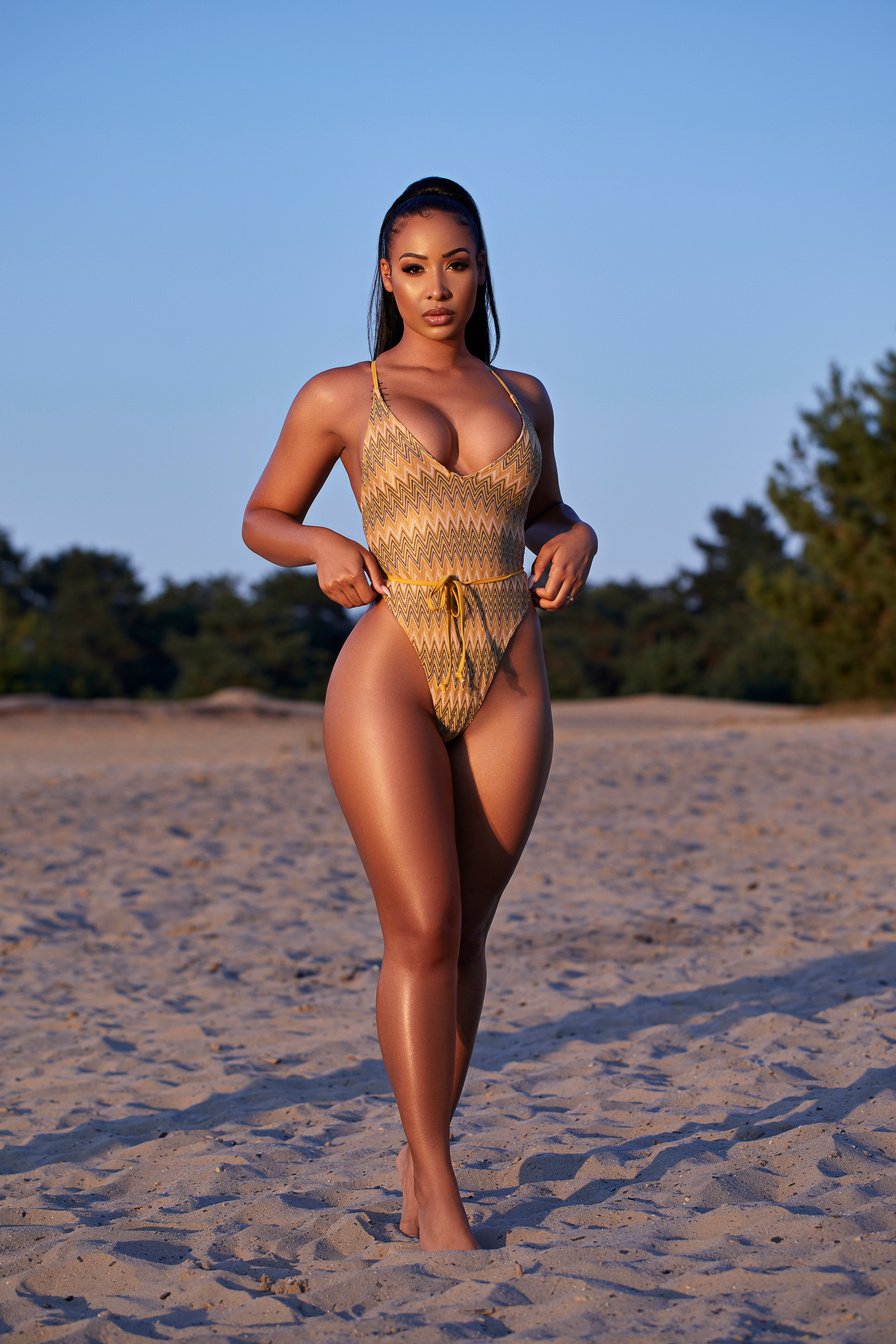 A Latin woman wearing a swim suit on a beach during sunset